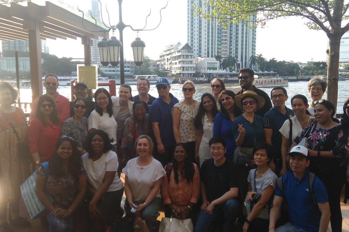 Corporate team posing together on a riverside deck in Bangkok during a team-building retreat