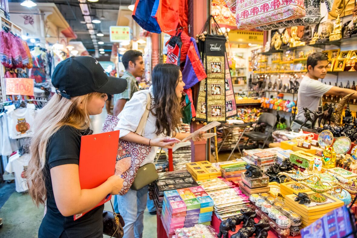 Group of colleagues collaborating to find clues and complete tasks in a busy Bangkok market during a team building activity