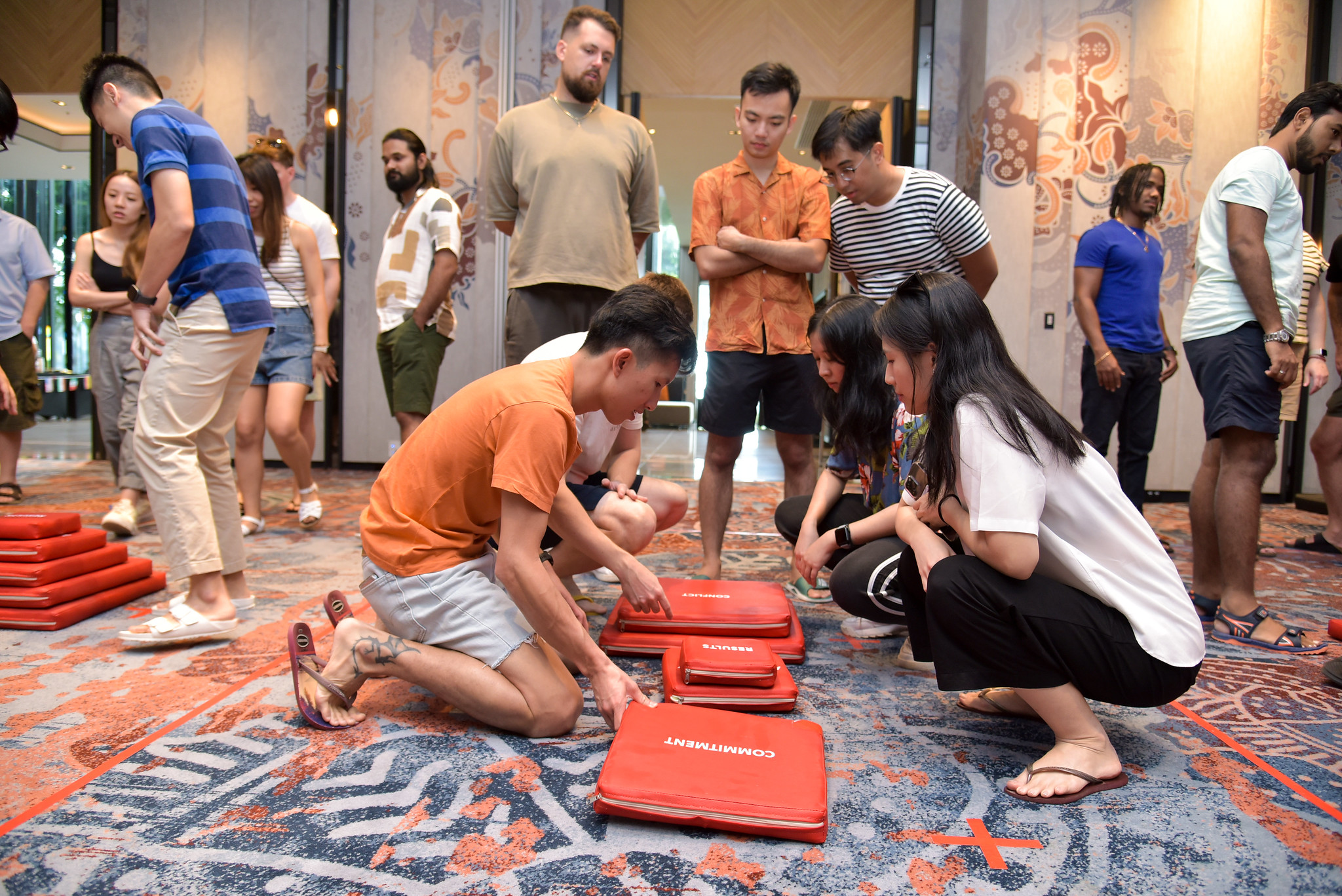 Benefits of Indoor Team Building for Corporate Groups Teams collaborate to assemble red foam pads on the floor during an indoor problem-solving and teamwork challenge.