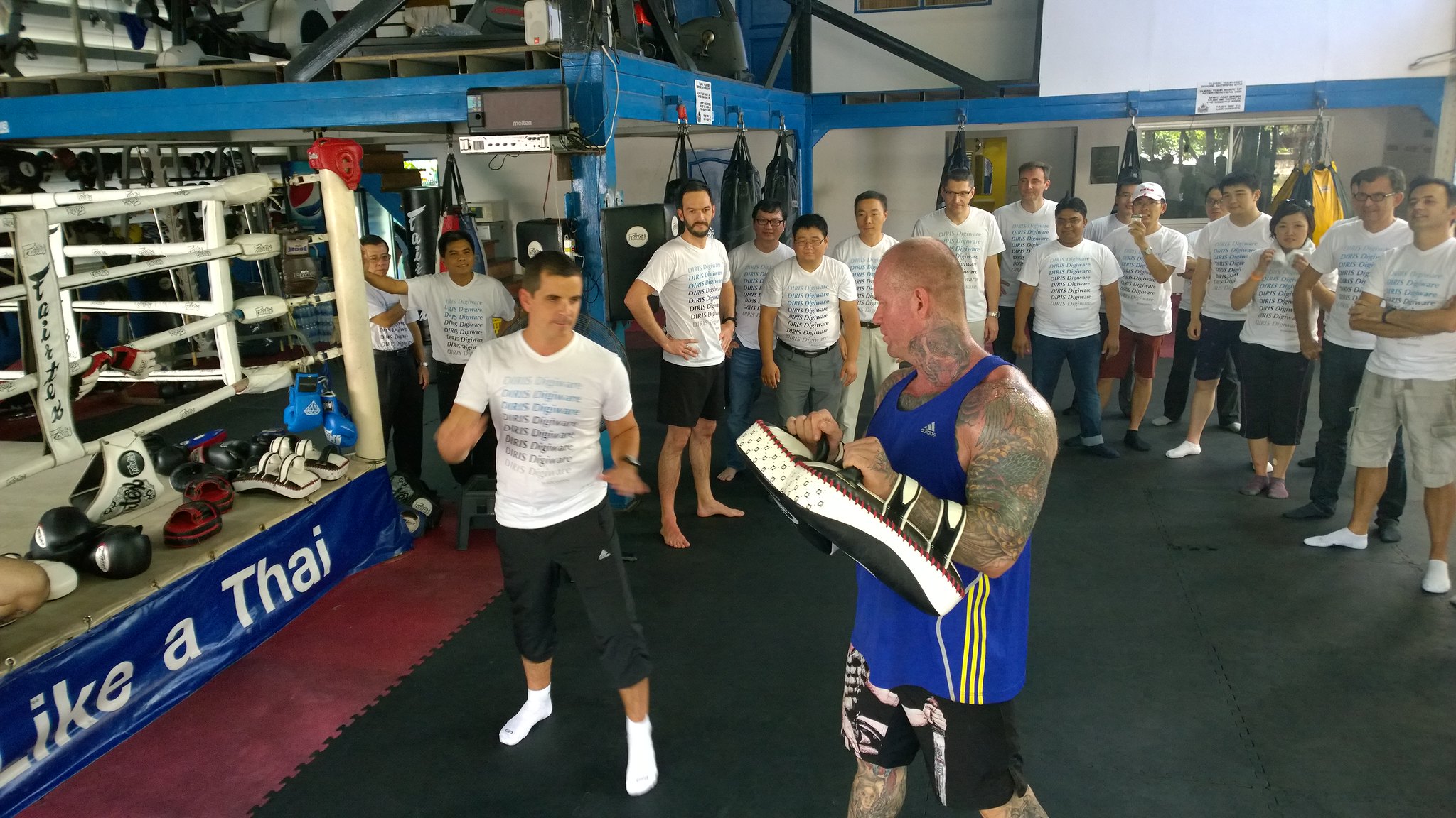 Cultural Intelligence and Adaptive Collaboration Business professionals practicing Muay Thai techniques together to build discipline, focus, and resilience in a team-building program.