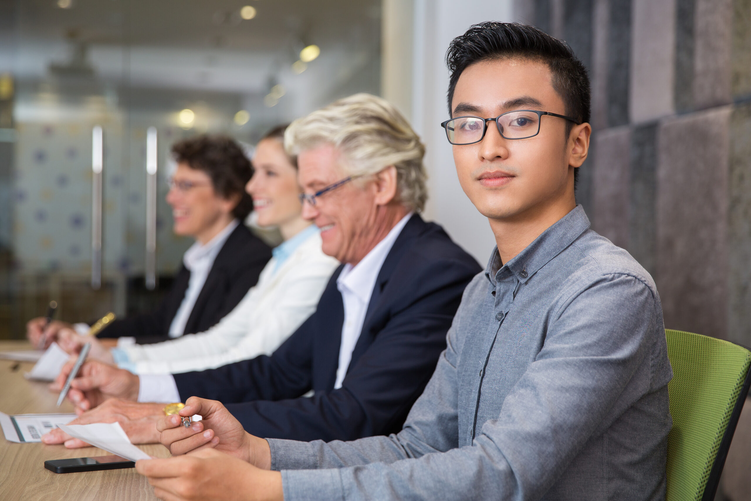Confident Asian manager sitting at meeting Business professionals reviewing event plans and presentation materials in a modern convention facility.